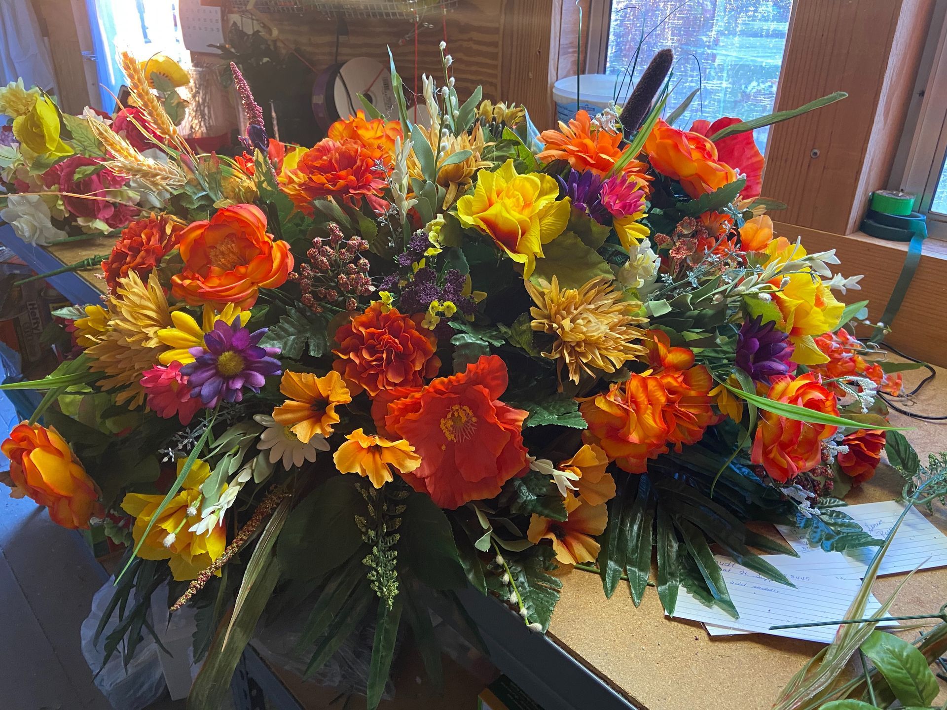 Bright mixed floral arrangement with orange, yellow, red, and purple flowers in a vase on a table
