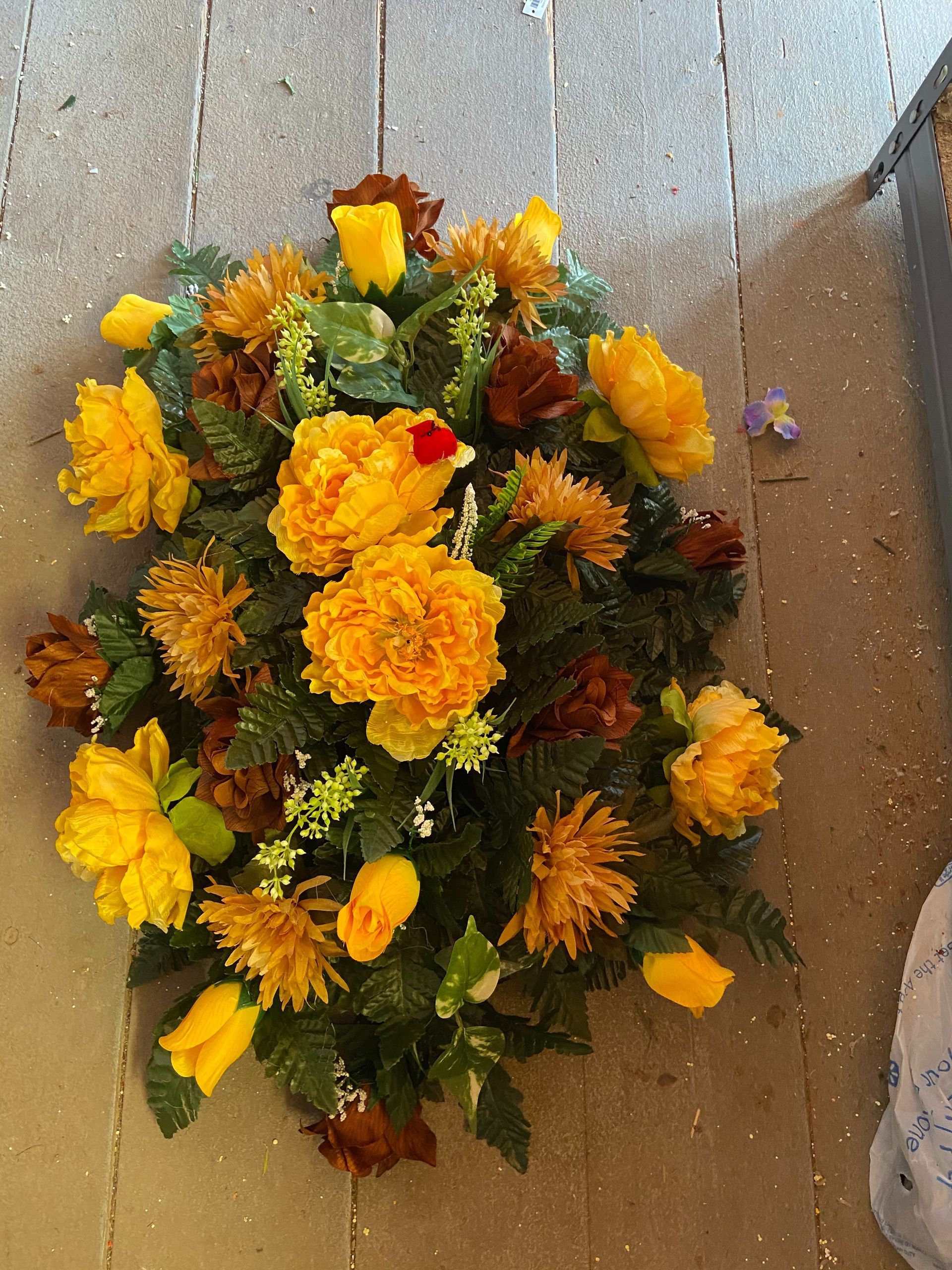 Yellow and orange flower garland arranged in a teardrop shape on a gray stone floor