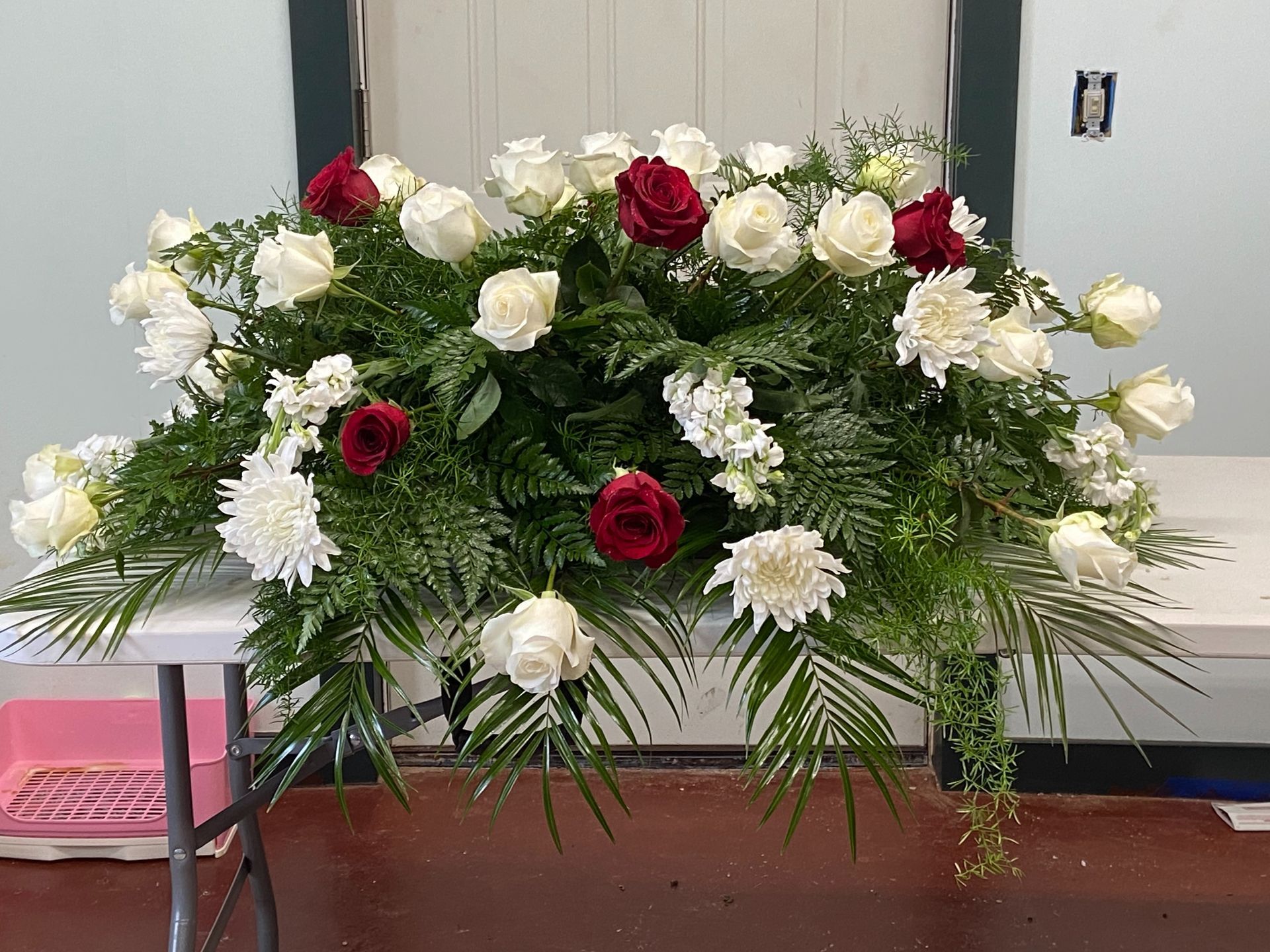 White and red flower arrangement on a table against a wall