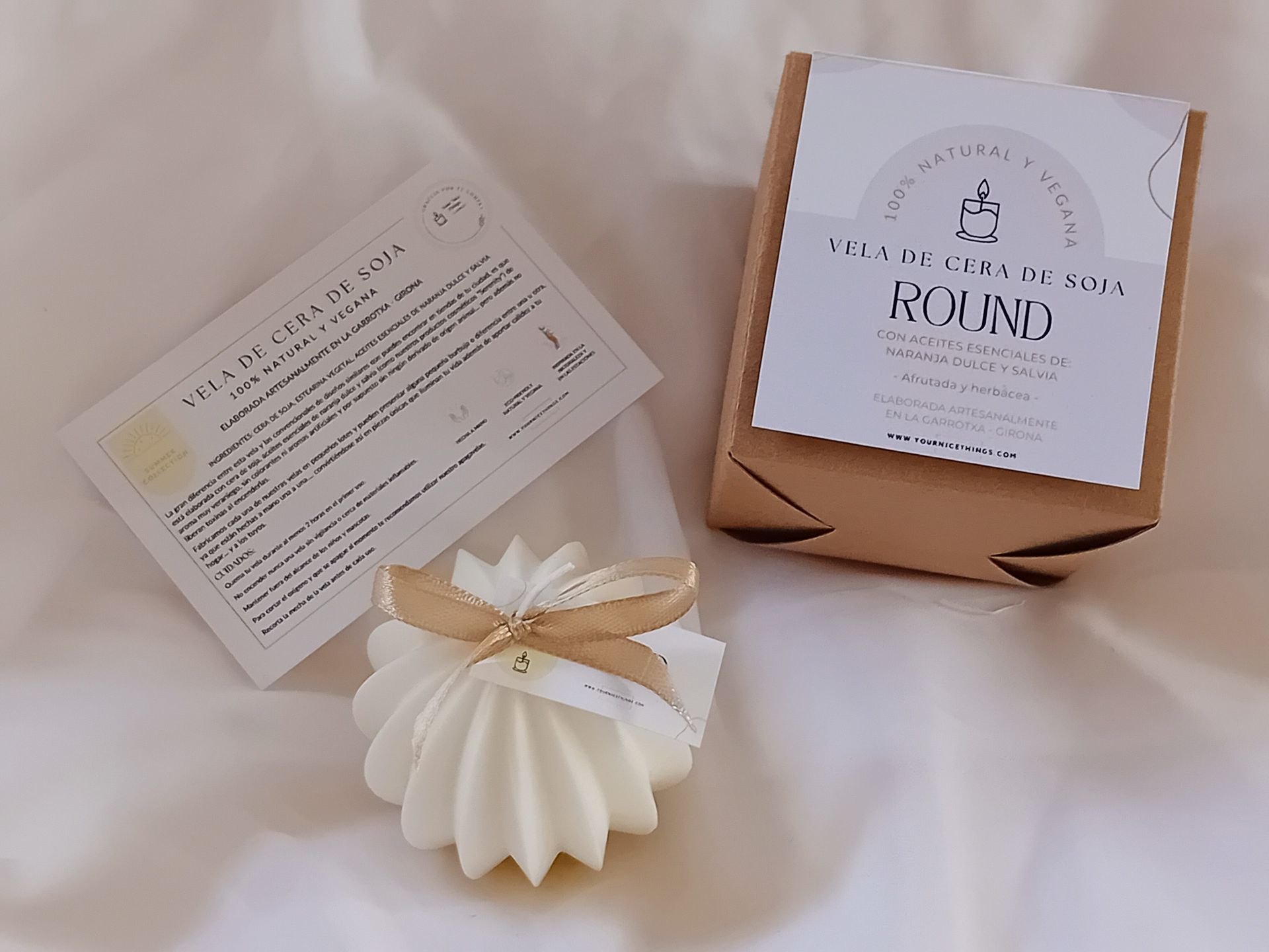 Wit geribbeld ornament met gouden lint en label aan een gedrapeerde crèmekleurige stof.