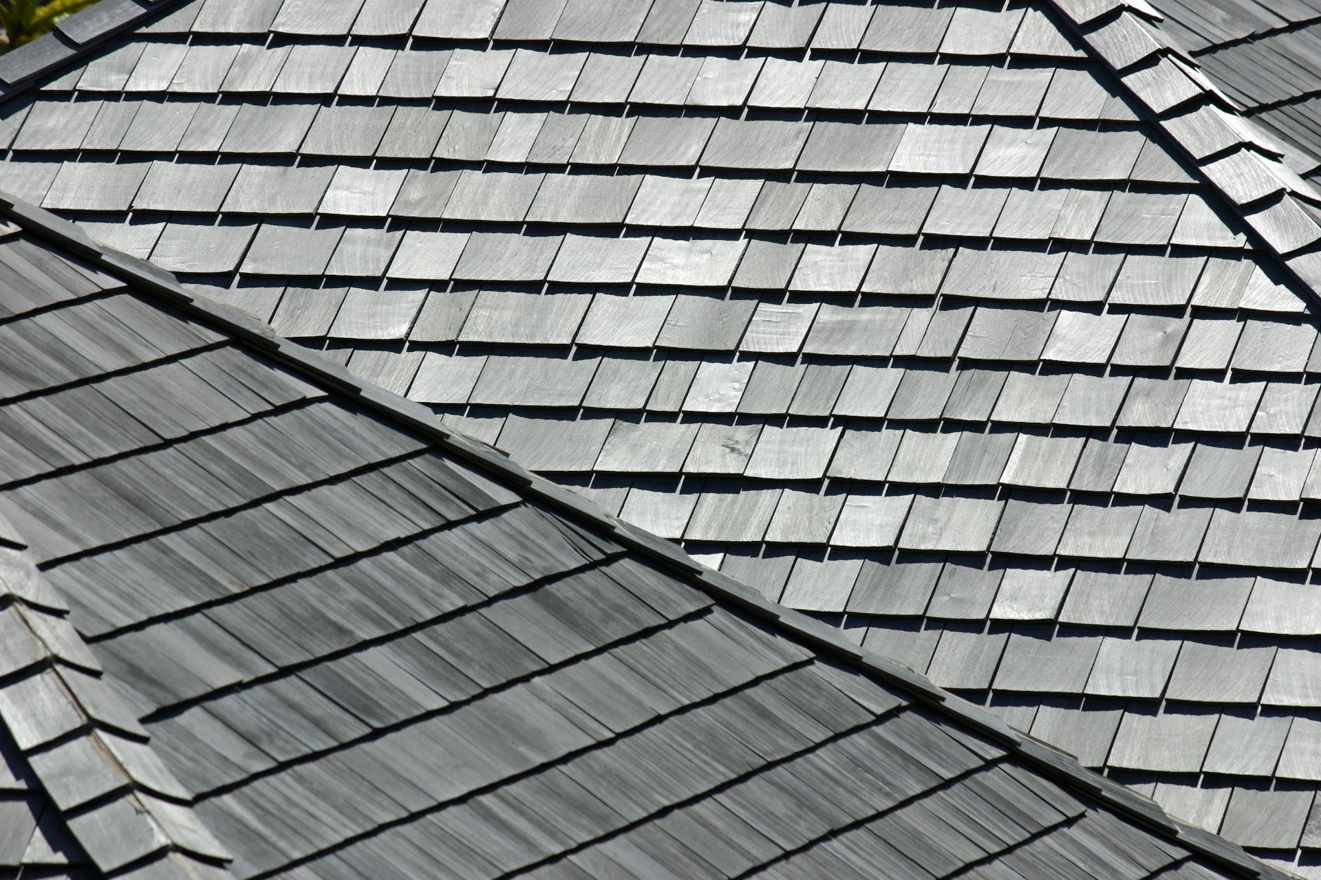Close-up of overlapping gray roof shingles on a sloped rooftop