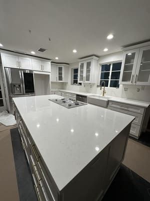 Bright modern white kitchen with large island, stainless steel appliances, and recessed lighting.