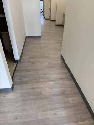 Empty beige hallway with wood-look flooring and multiple doorways