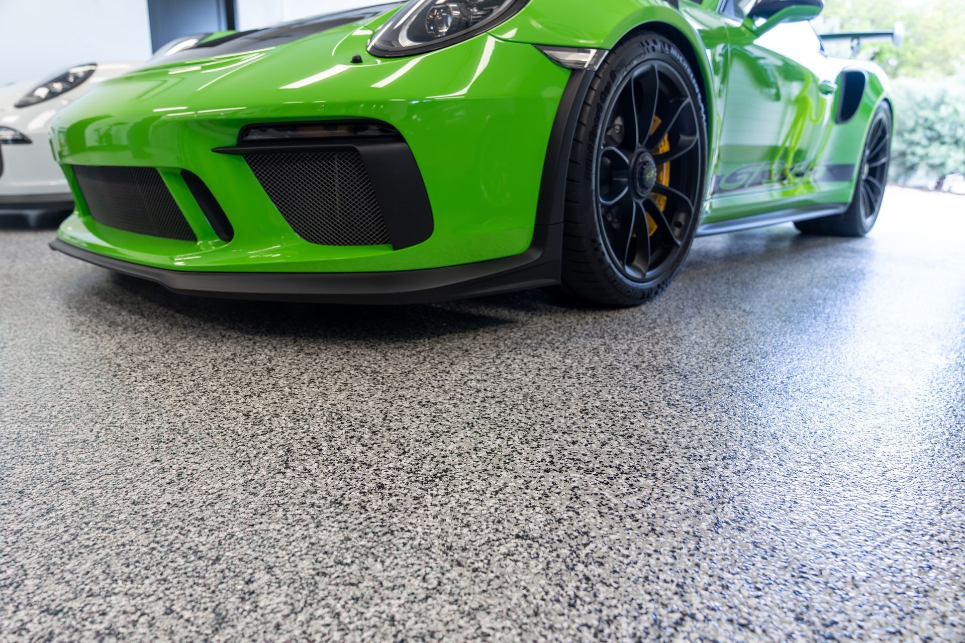 Bright green sports car parked indoors on a polished garage floor
