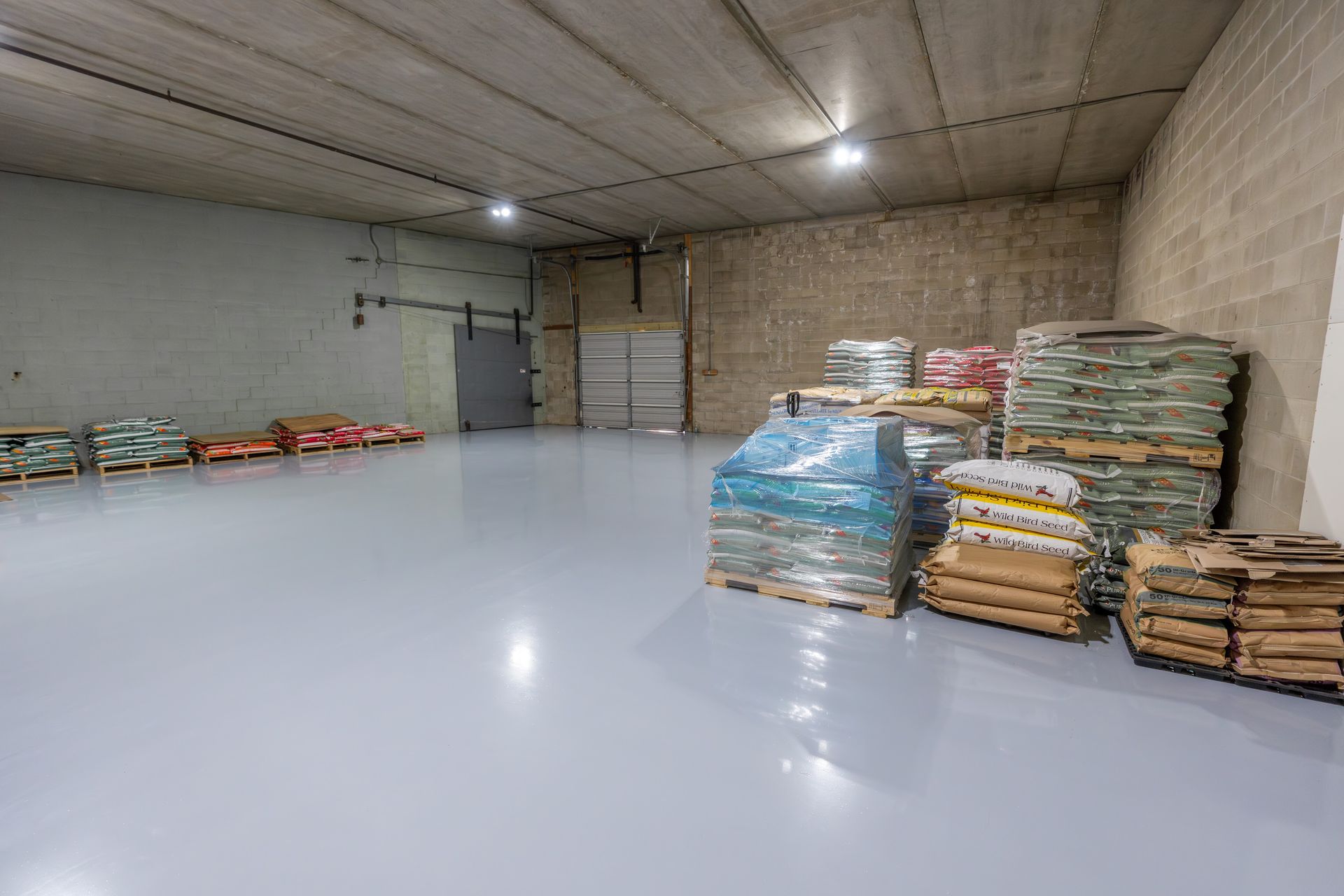 Empty warehouse with stacked bags and pallets along the walls on a polished white floor