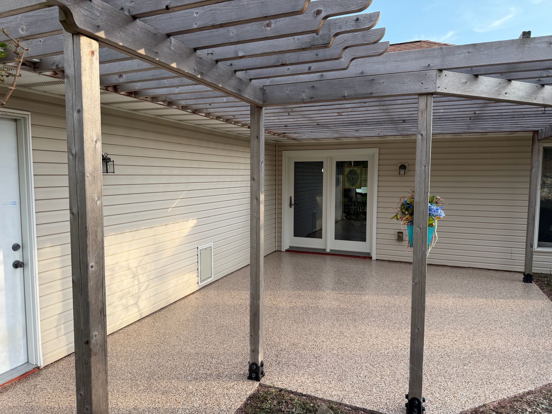 Covered patio with pergola, sliding glass doors, beige siding, and a tiled floor.
