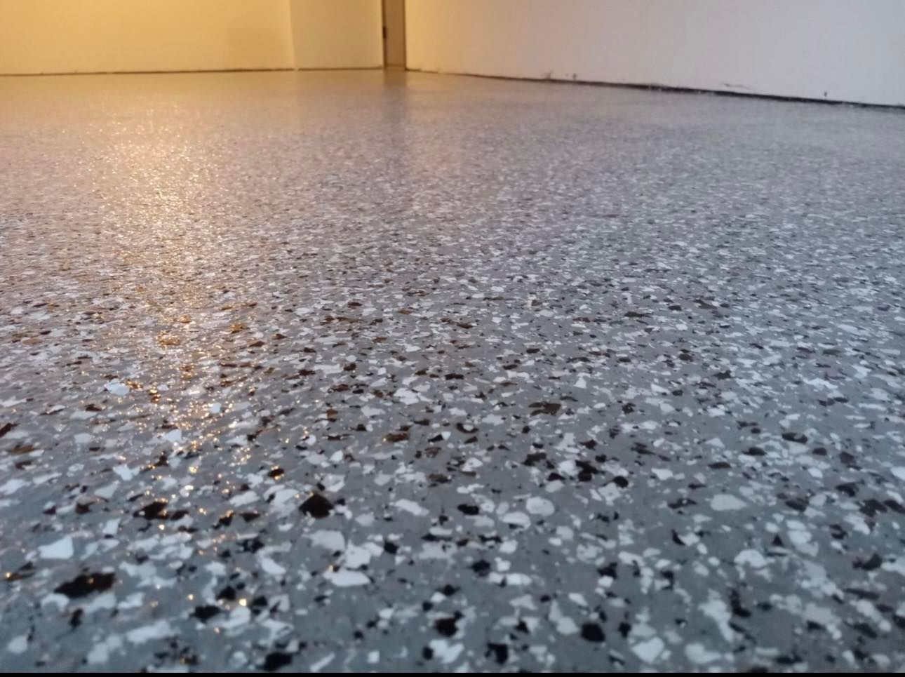 Gray speckled floor with yellow wall in the background, viewed from a low angle
