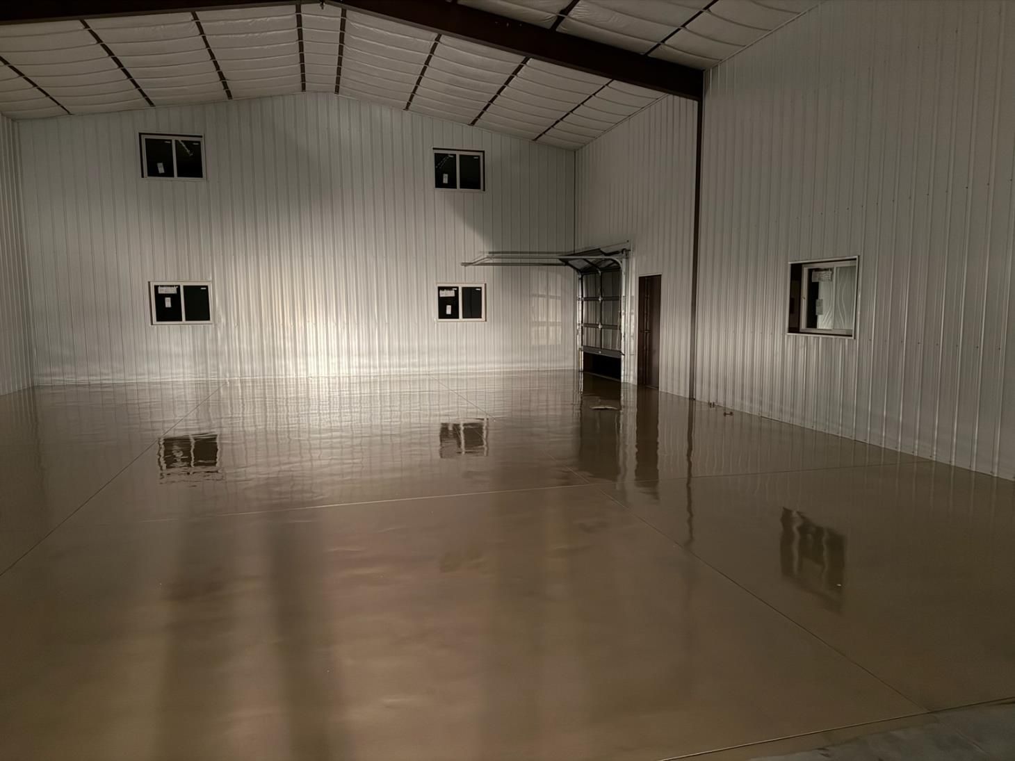 Empty indoor room with glossy floor, white walls, and small high windows.