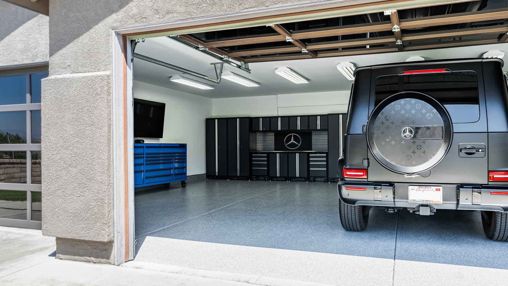 Car garage with open door, showing a gray Mercedes SUV parked inside and storage cabinets on the back wall
