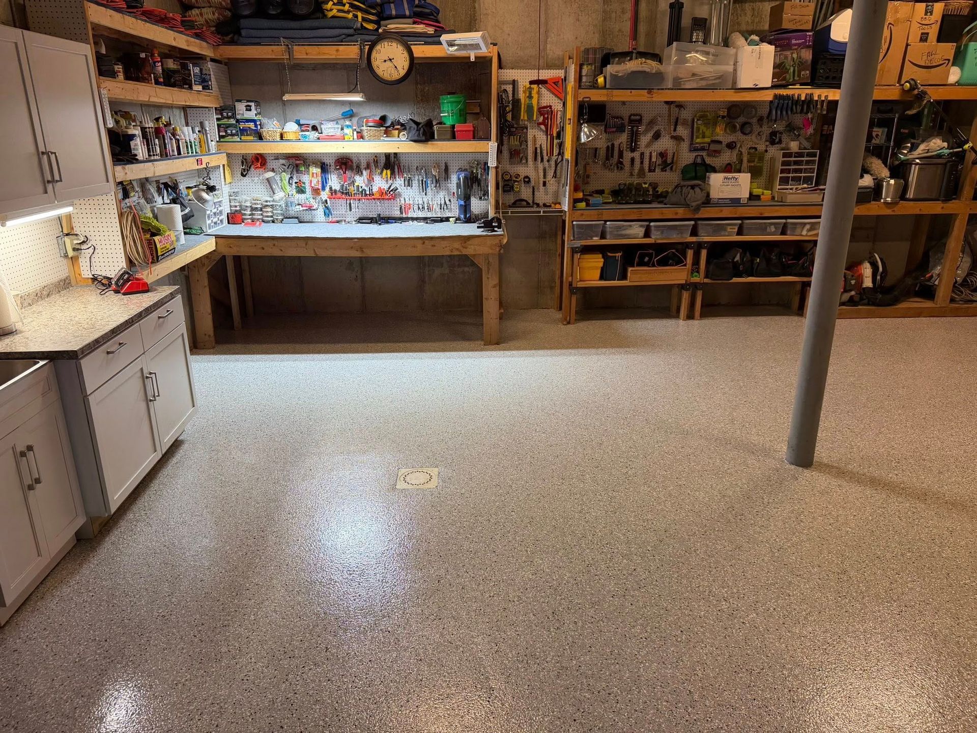 Storage room with shelves of assorted supplies, a counter, cabinets, and a speckled floor