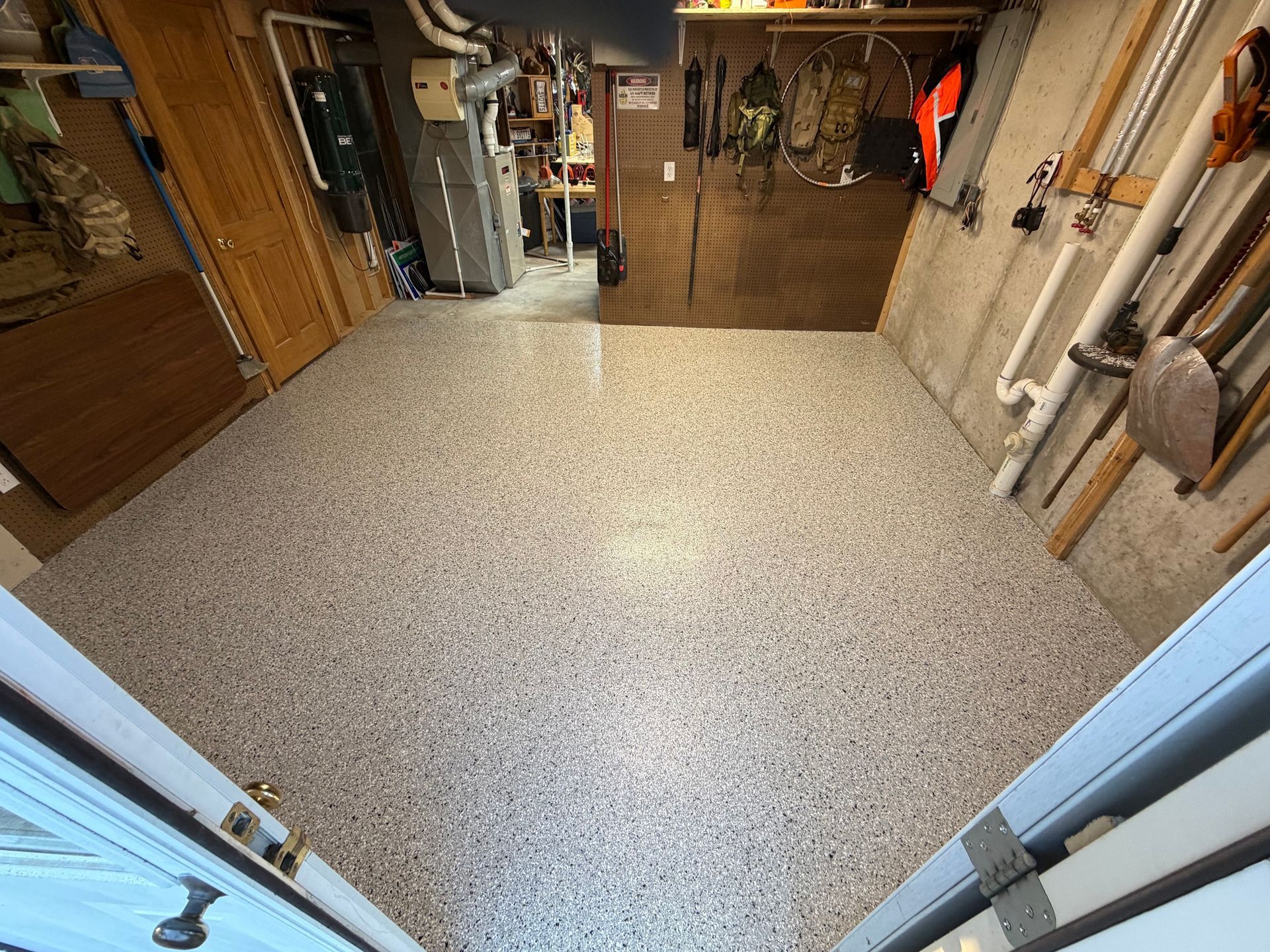 Garage workshop with speckled floor, shelves, tools, and folded metal gate at the back.