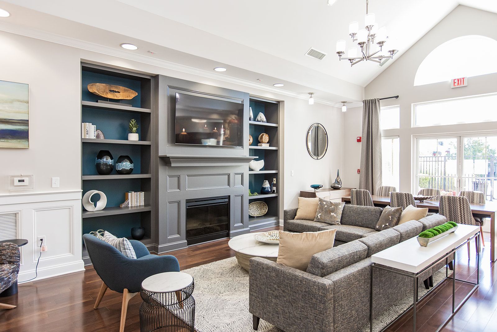 Bright living room with blue built-ins, fireplace, sectional sofa, and large windows at Apartments at Charlestown Crossing.