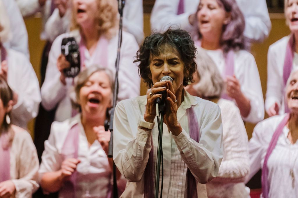 Singer performing in front of a lively choir in white and pink robes