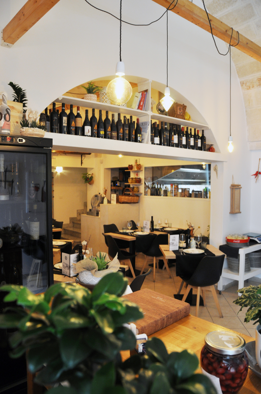 Accogliente interno del ristorante con bancone ad arco, lampade a sospensione e tavoli in un ambiente caldo e moderno.
