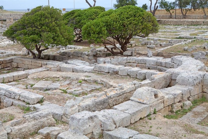 Veduta aerea di un complesso di rovine in pietra con fondamenta rettangolari in mezzo a un terreno erboso.
