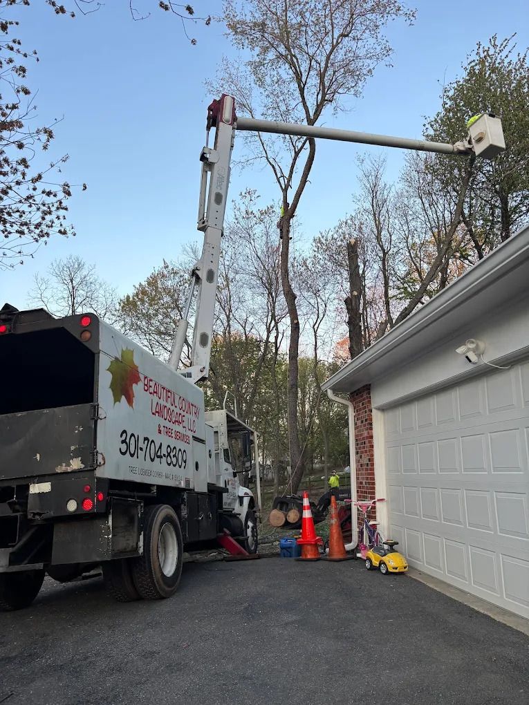 Utility truck and bucket lift beside a garage, with workers’ cones and tools on a driveway.
