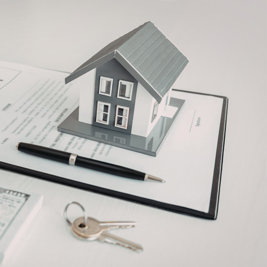 Miniature house model on paperwork with a pen and keys, suggesting real estate or home purchase.