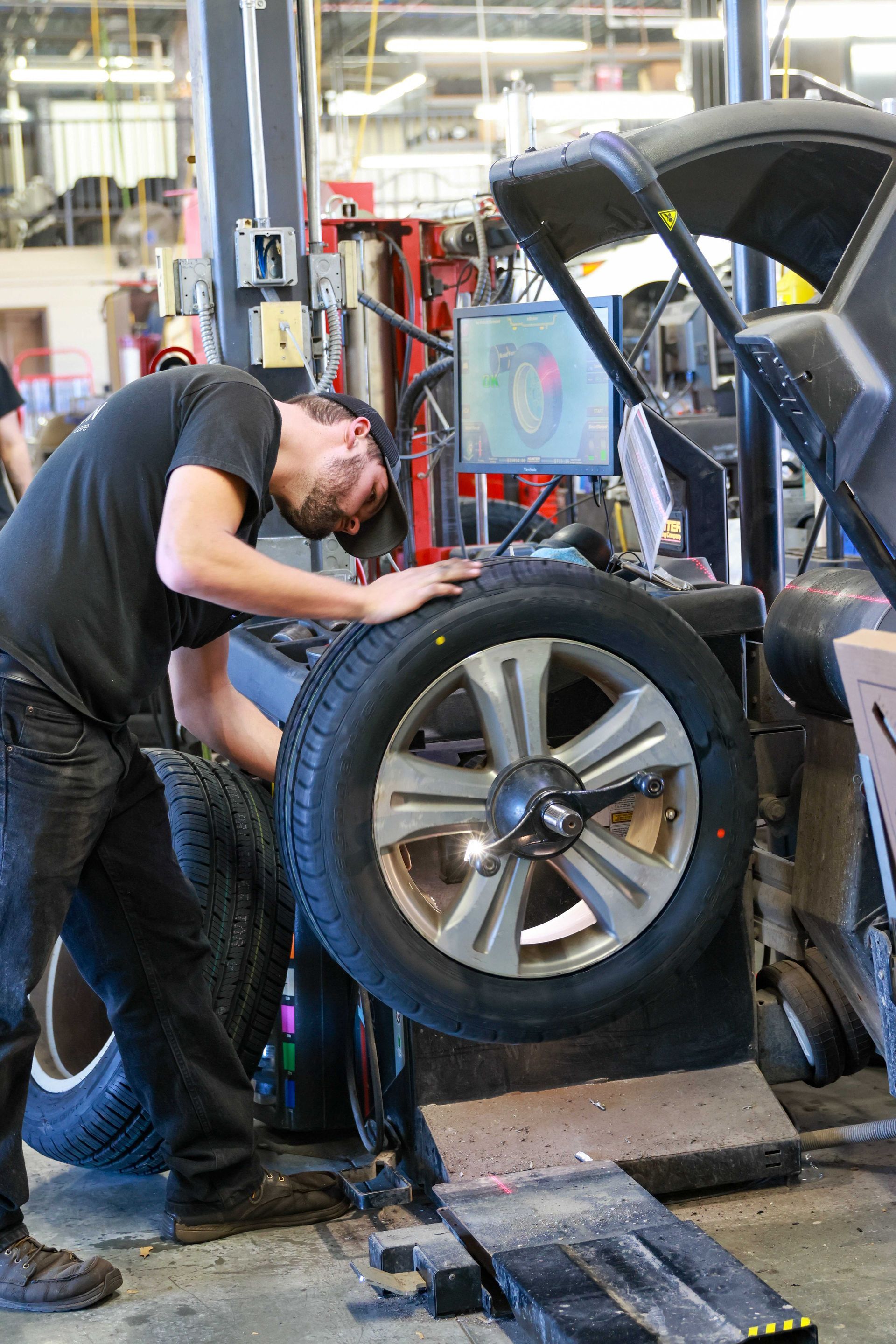 Mechanic working on a car with the wheel removed in an auto repair shop