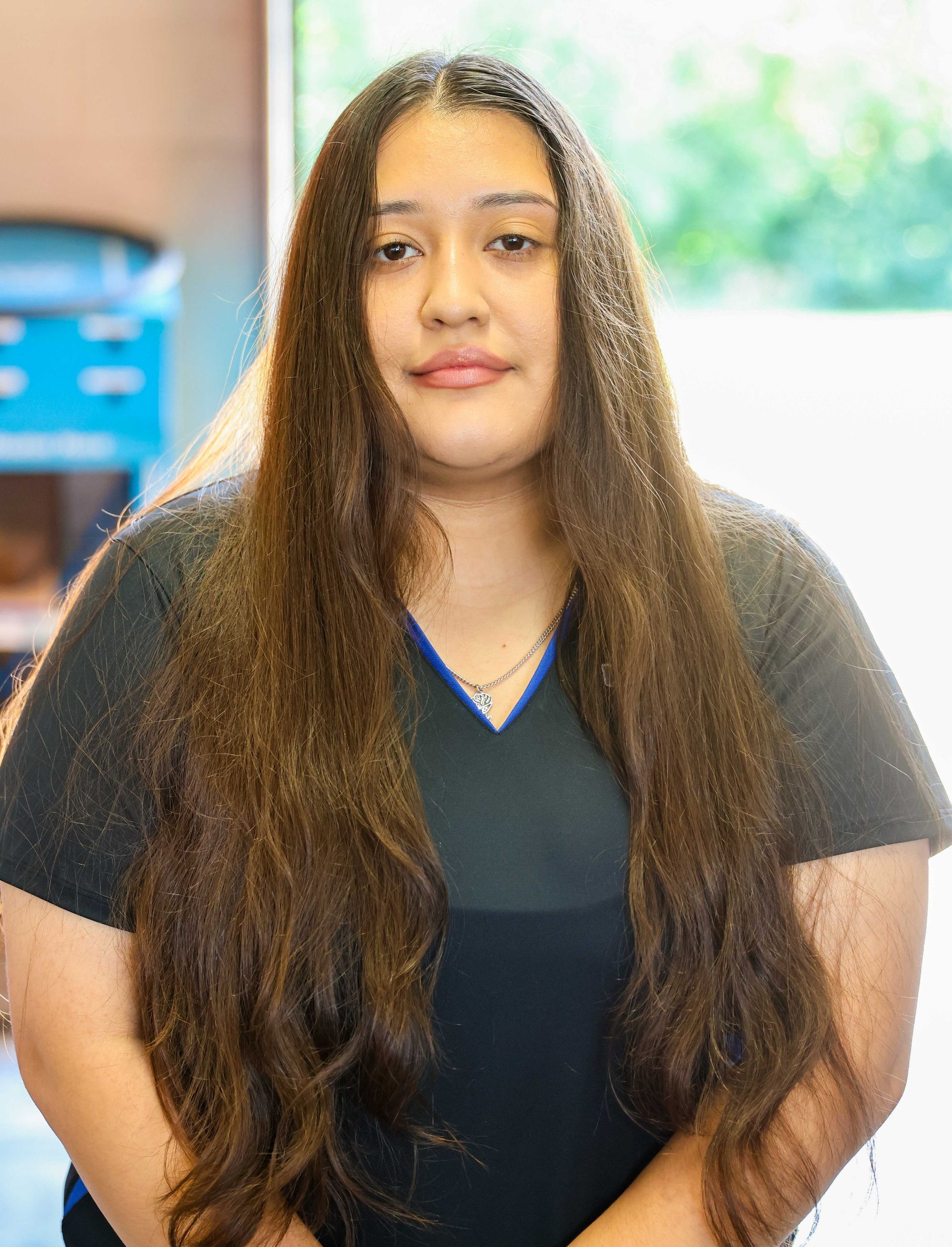Smiling man in glasses wearing a black T-shirt with a company logo, standing indoors.