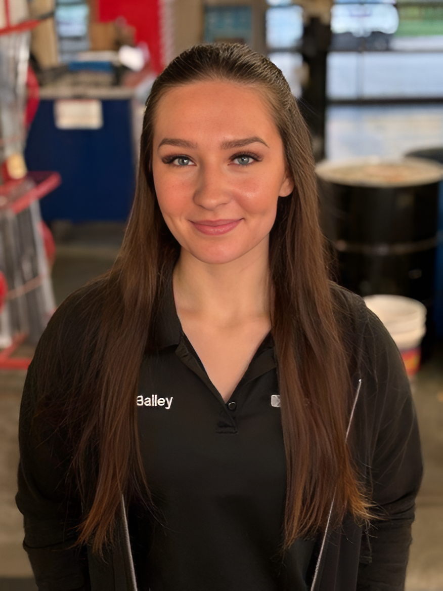 Smiling woman in a black shirt standing indoors with gym equipment in the background