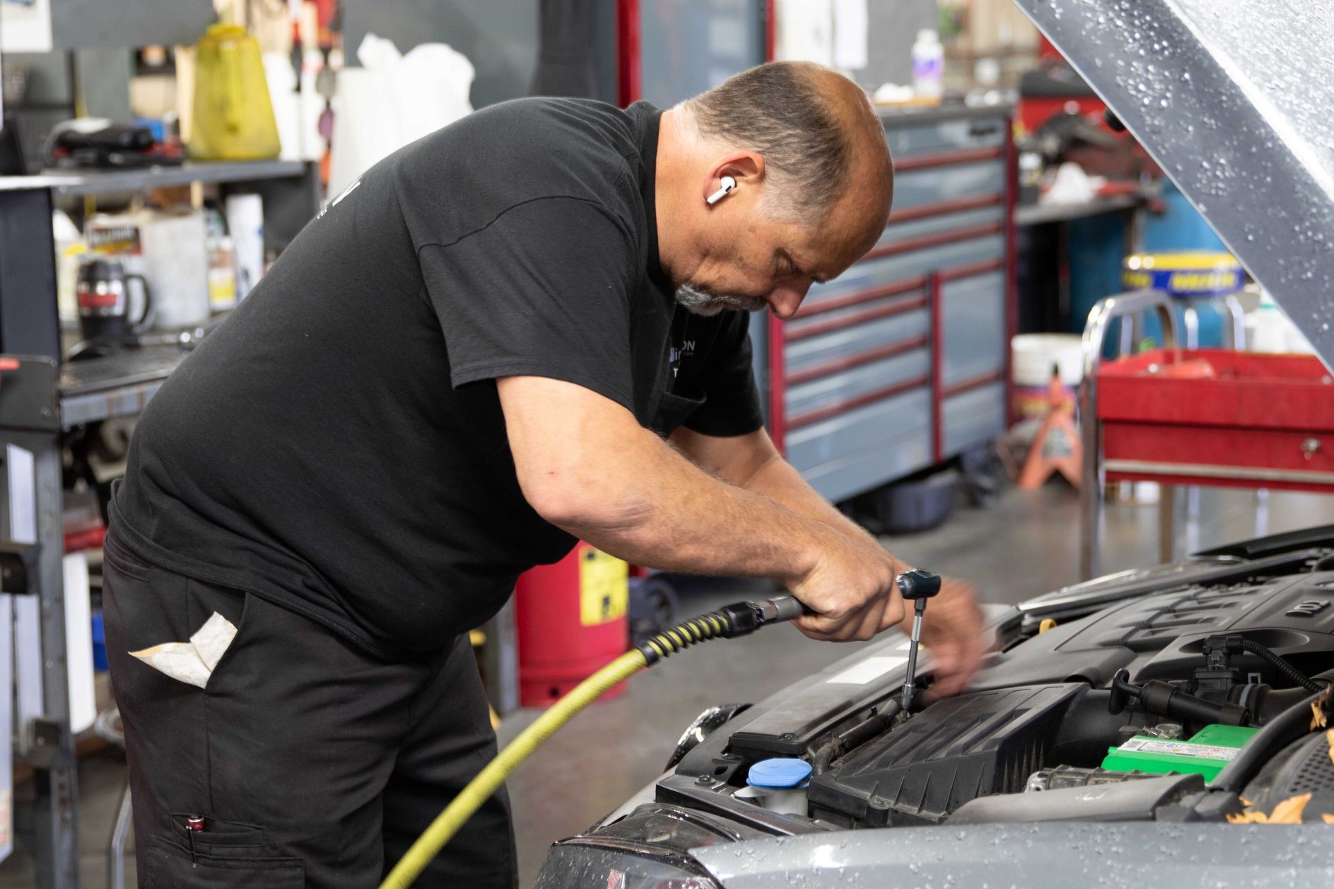 Mechanic working under a car hood in an auto repair shop