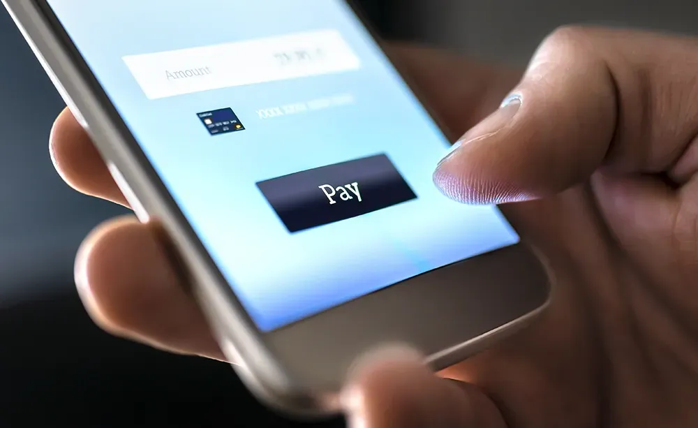 A hand holds a smartphone, finger poised to press a black