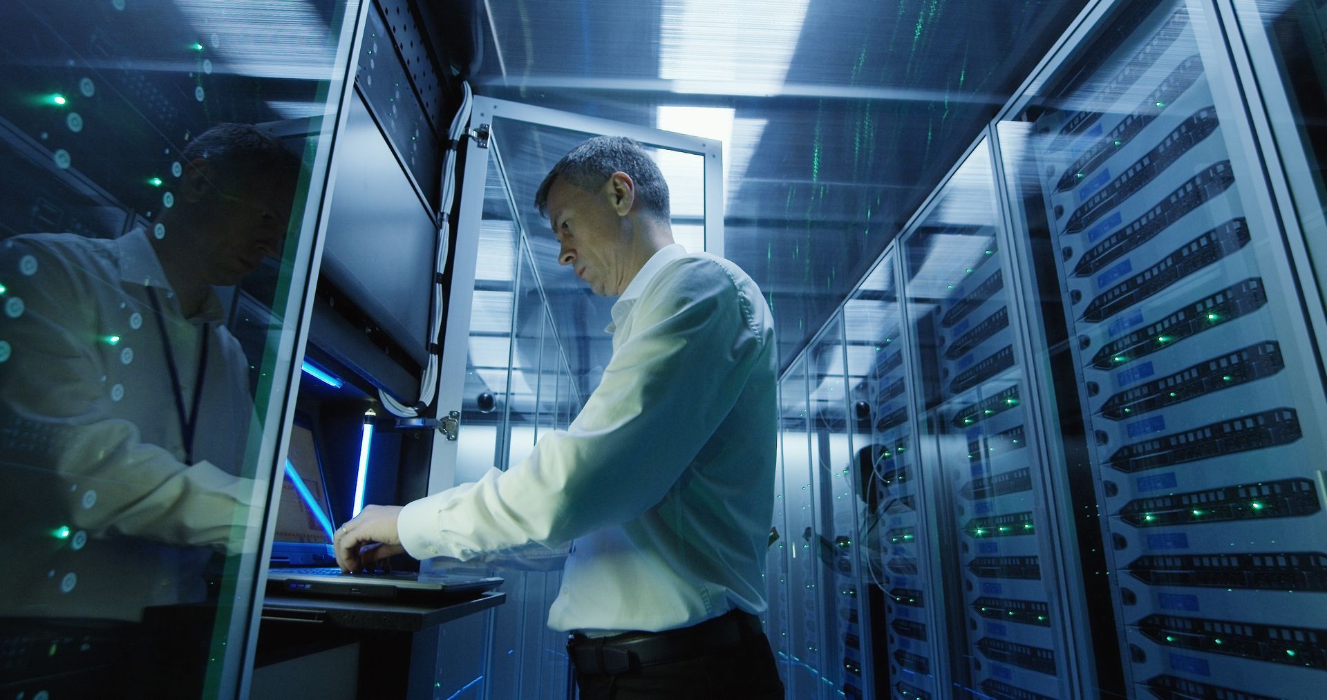 A man in a white shirt works in a server room, demonstrating Team Office Technologies' managed IT se