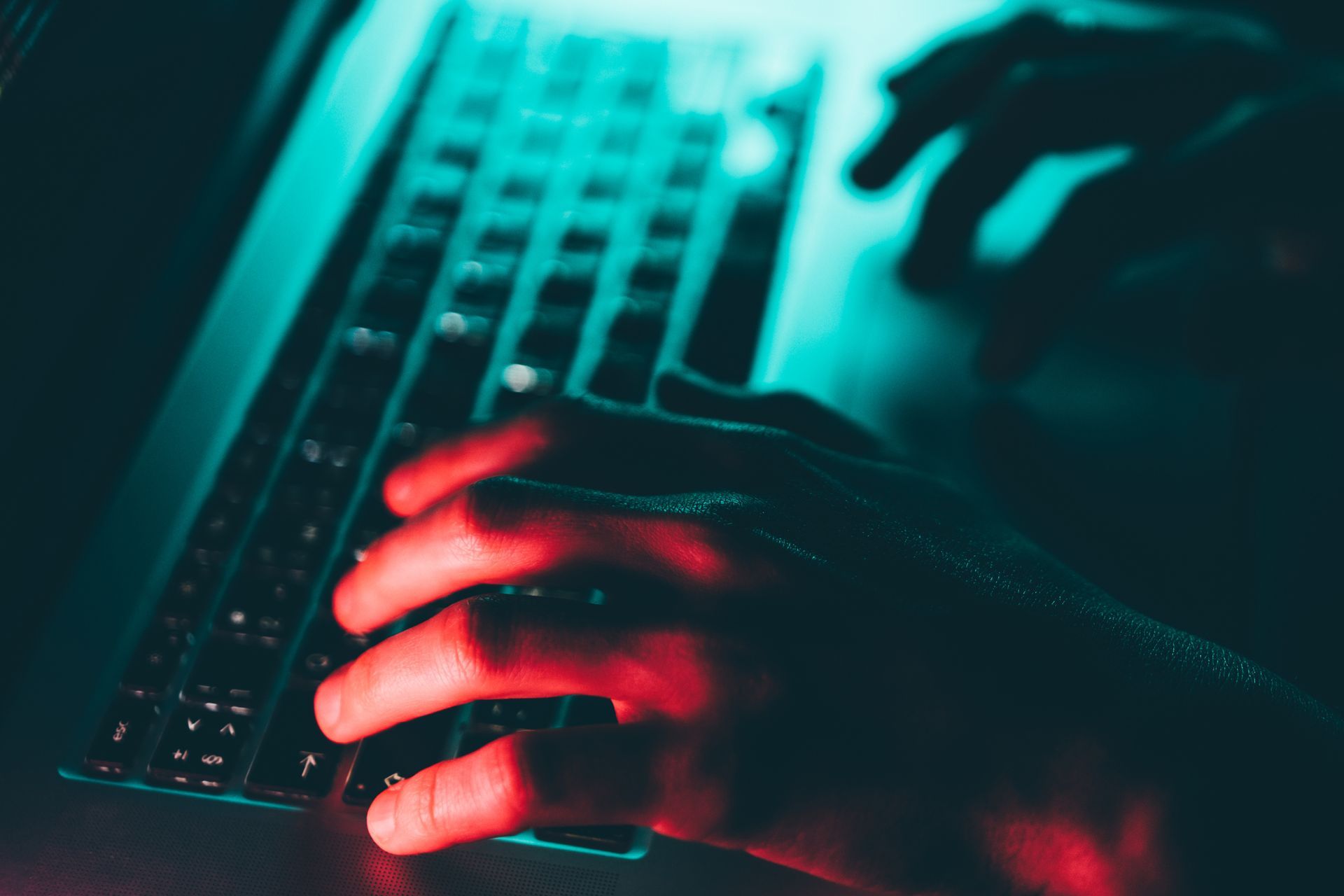 A person is typing on a laptop computer in the dark.
