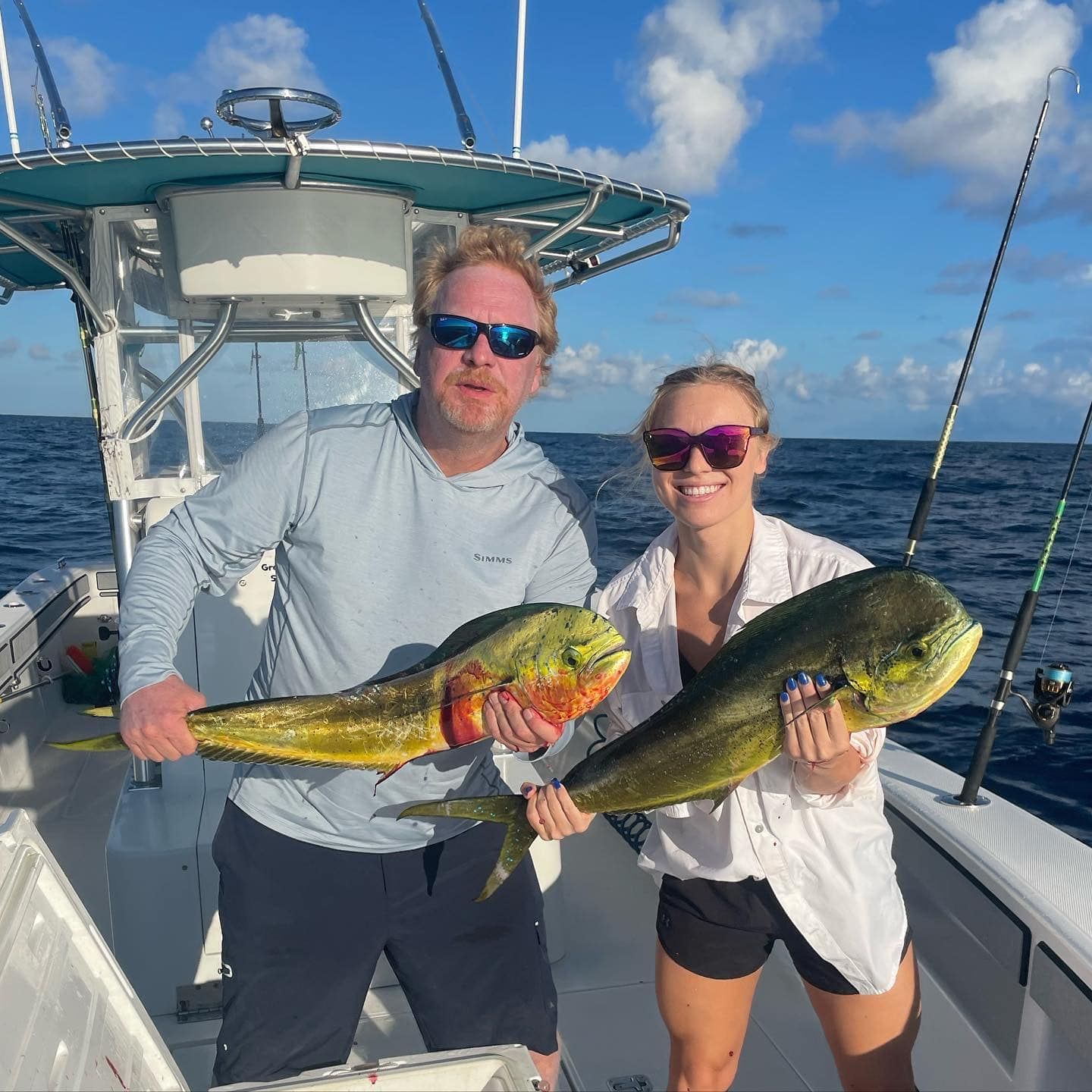 Two anglers on a boat holding large mahi-mahi on a sunny day at sea