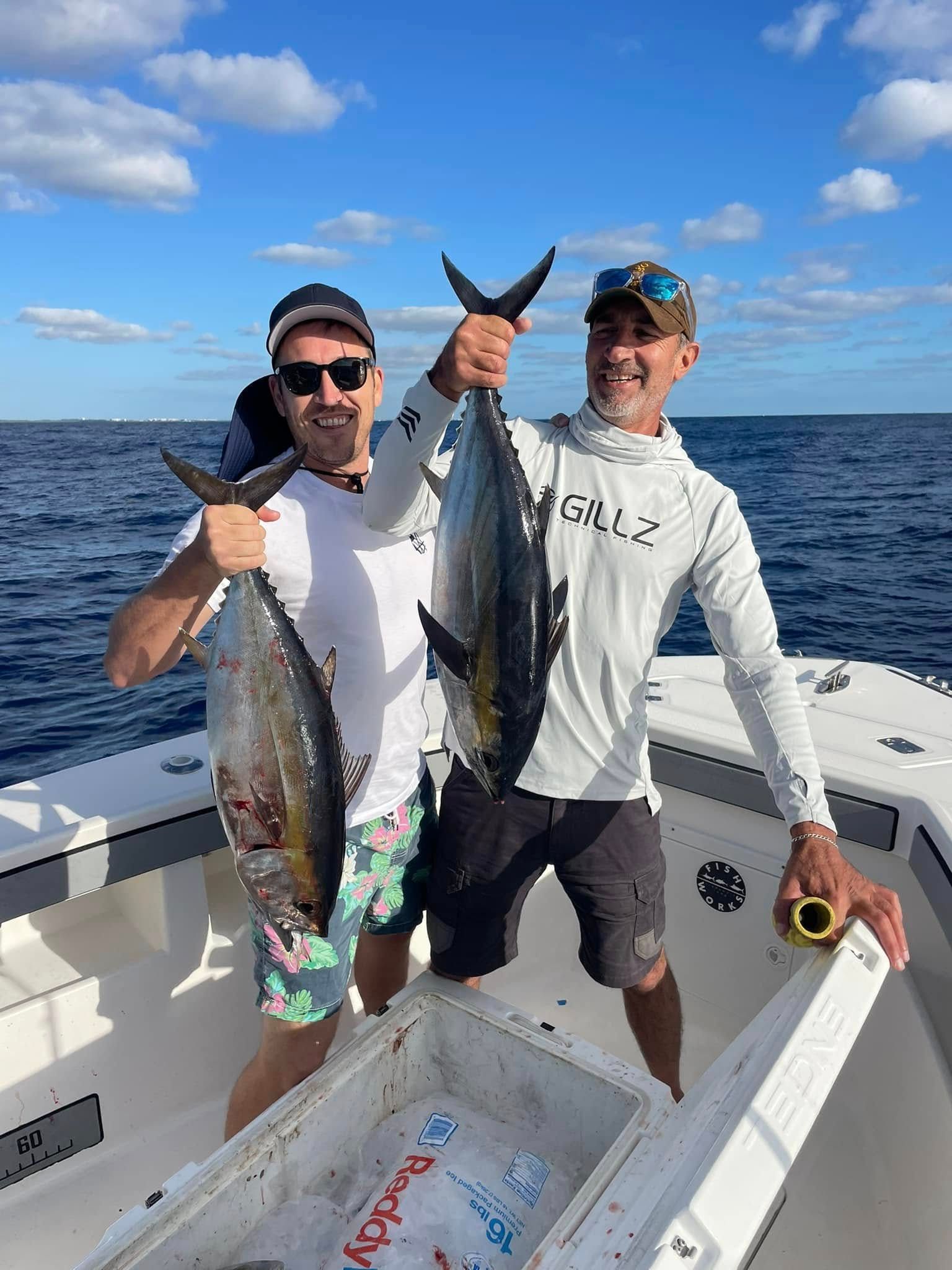 Two anglers on a boat hold up a large fish on a sunny ocean trip