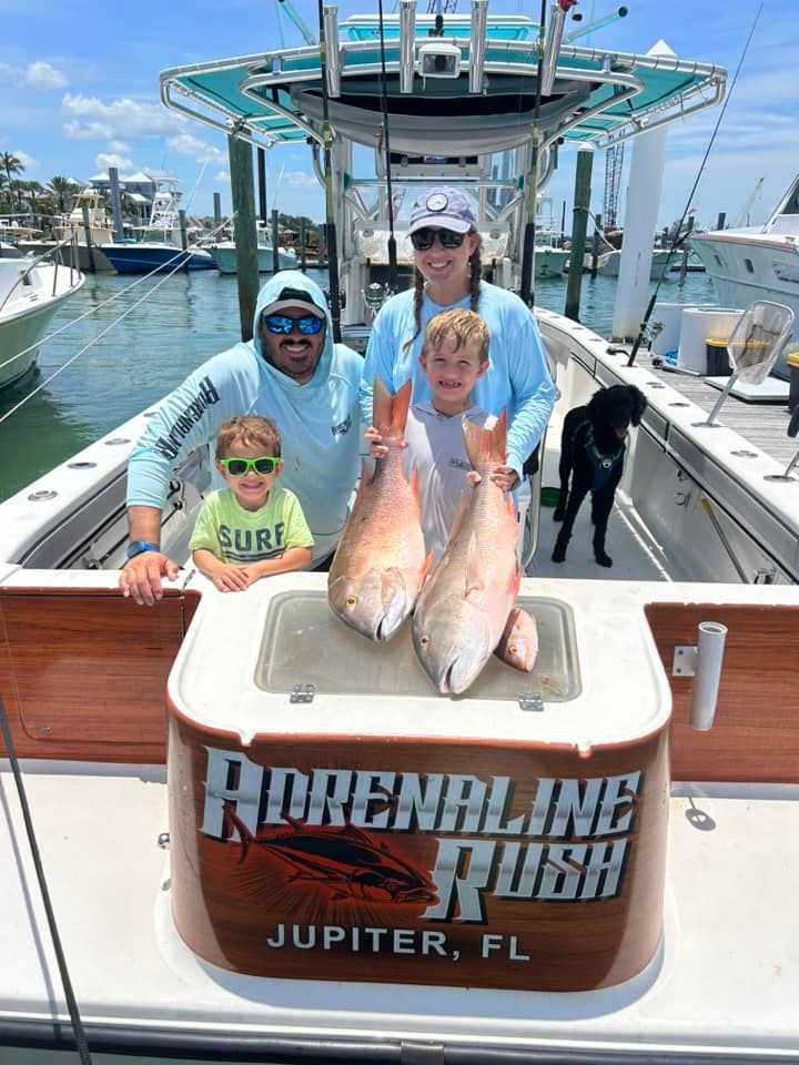 Four people on a fishing boat posing with two large fish at Jupiter, FL, with 