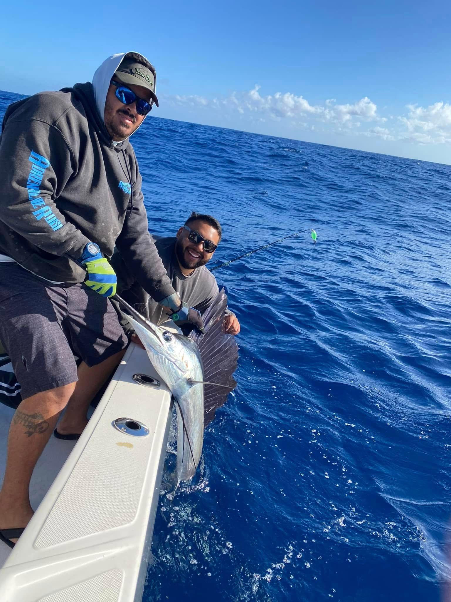 Two people on a boat fishing in blue ocean water under a bright sky