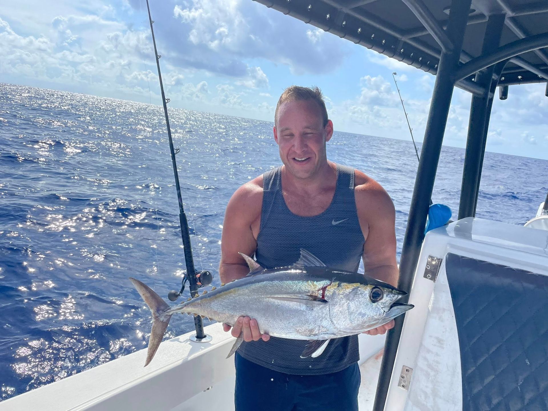 Person on a boat holding a large fish with ocean and blue sky in the background