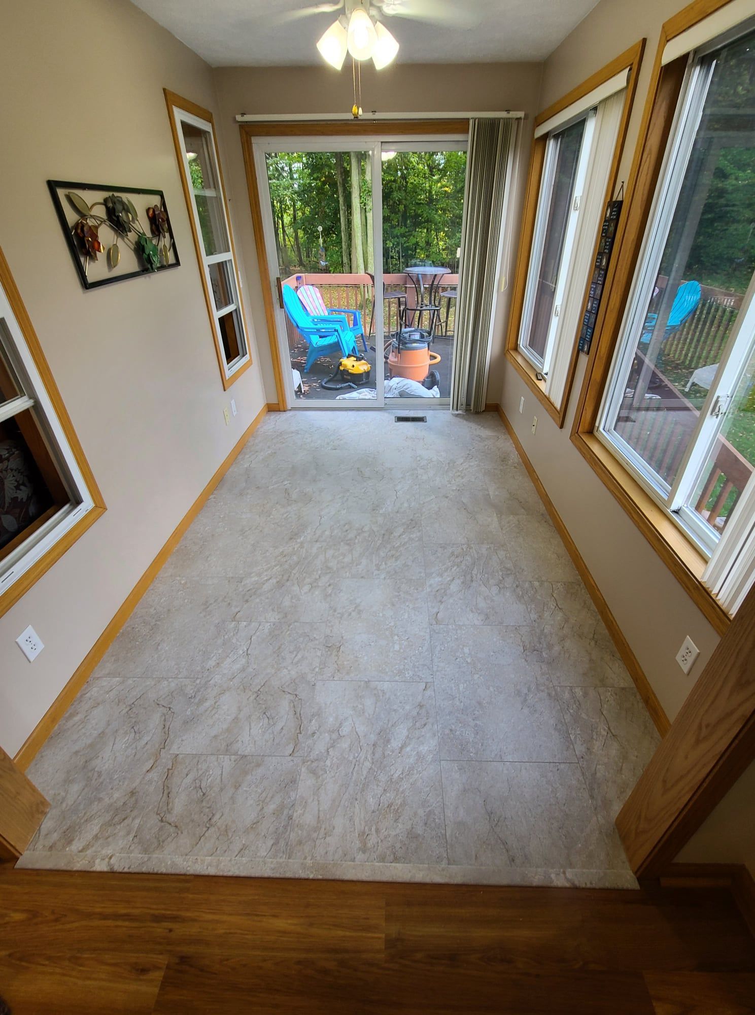 Small sunroom with sliding glass door to a deck; light beige carpet, wooden trim, windows, and a beige wall.