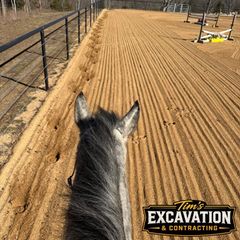 Horse's view down a freshly graded tan dirt road beside a black fence, with excavation sign visible.