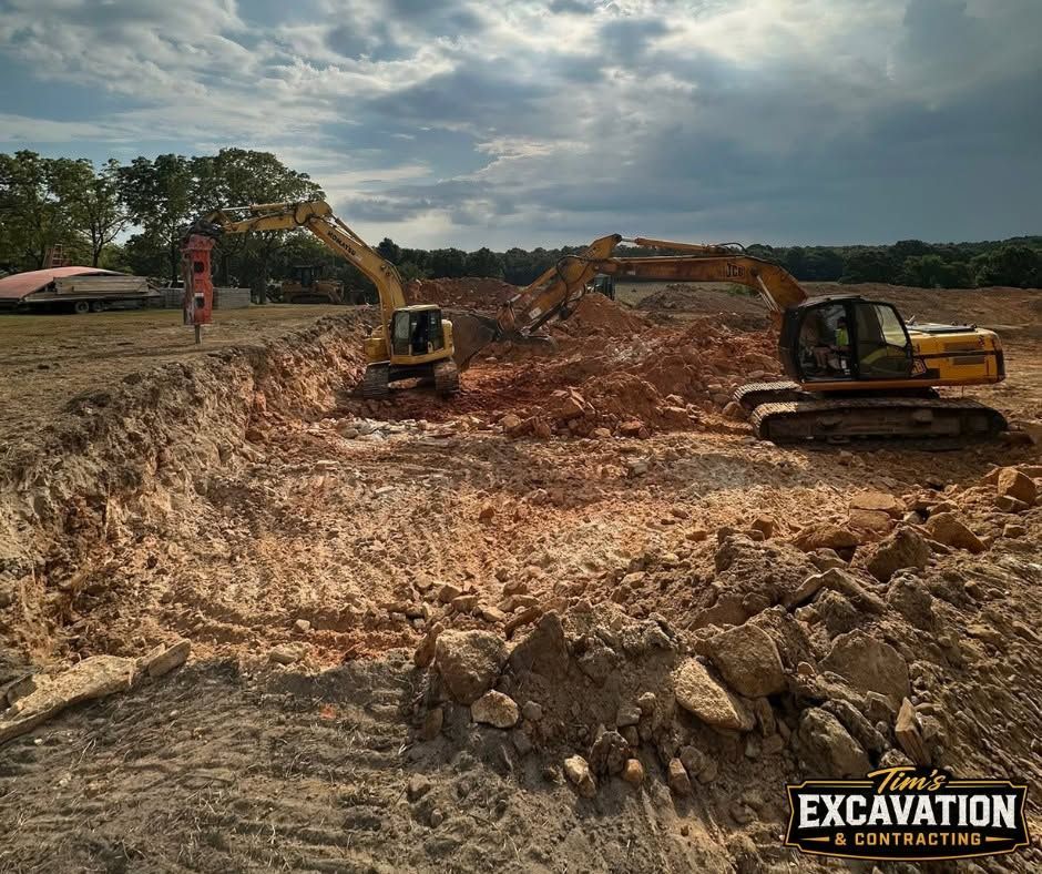 Excavators working in a large dirt pit at a construction site under cloudy skies