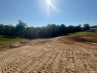 Horse's view down a freshly graded tan dirt road beside a black fence, with excavation sign visible.