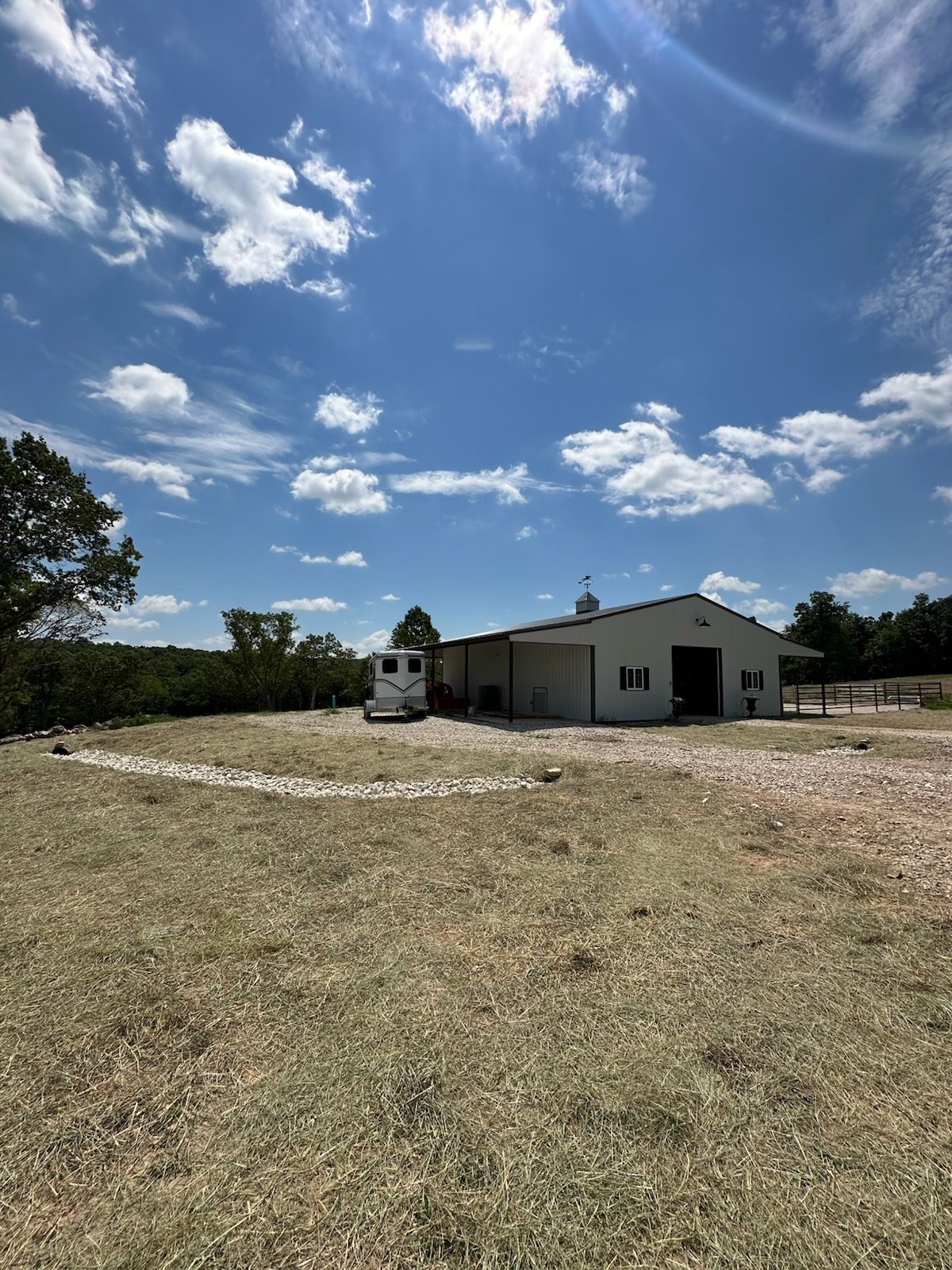 Rural house with a gravel yard under a bright blue sky with scattered clouds