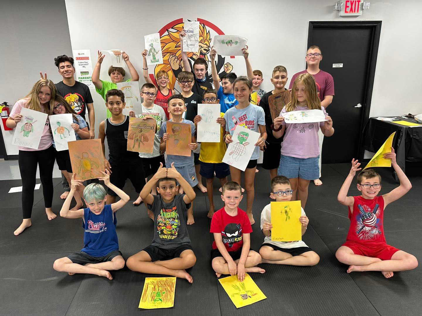 a group of kids holding up their drawings in front of an exit sign