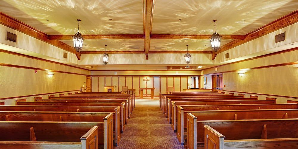 Empty wooden church interior with pews facing a central aisle and altar