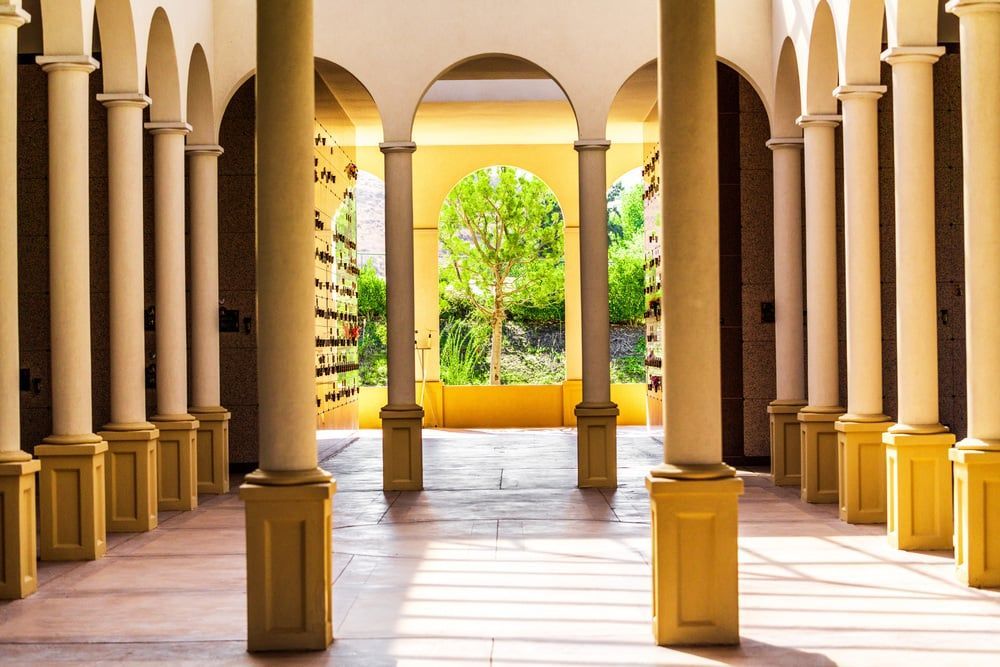 Sunny arched colonnade opening to a lush courtyard with yellow planters and tiled floor