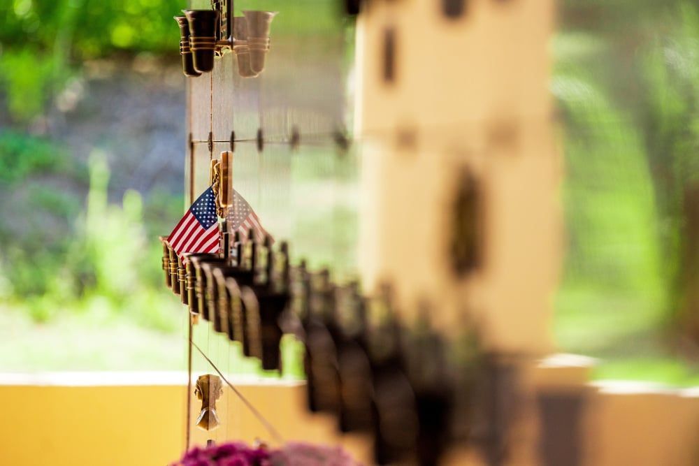 Small American flags and wooden ornaments hanging on a sunlit decorative display outdoors.