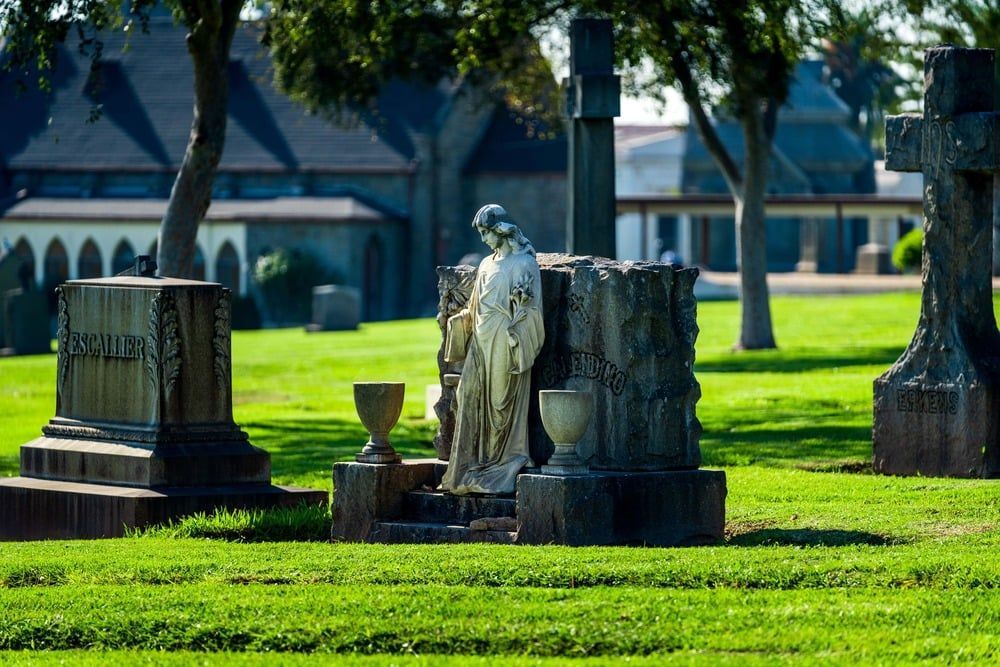 Stone angel statue among old cemetery headstones on a sunny green lawn
