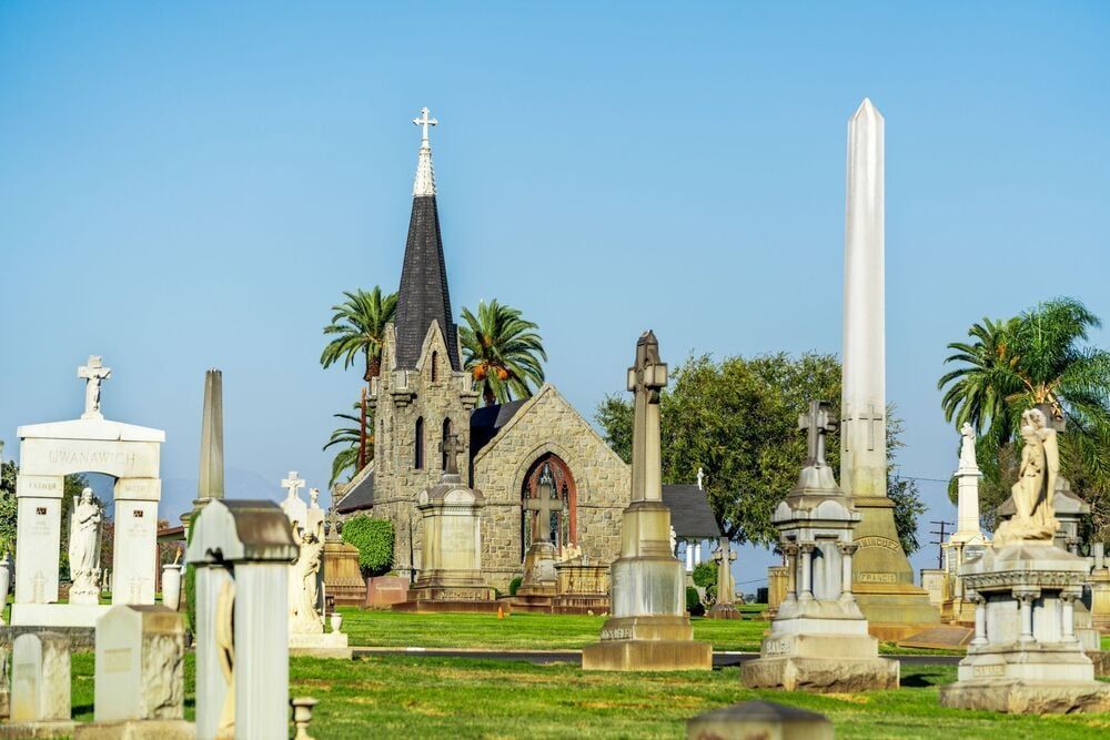 Historic cemetery with ornate tombstones and a church-like mausoleum under a blue sky