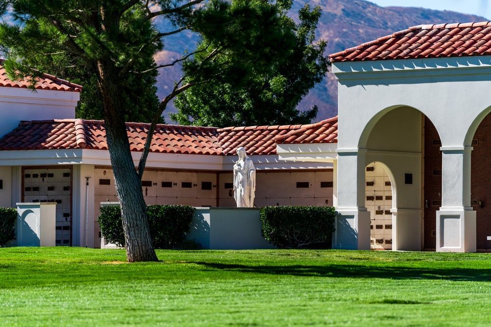 Spanish-style campus building with red tile roofs, arched entrance, and green lawn in front