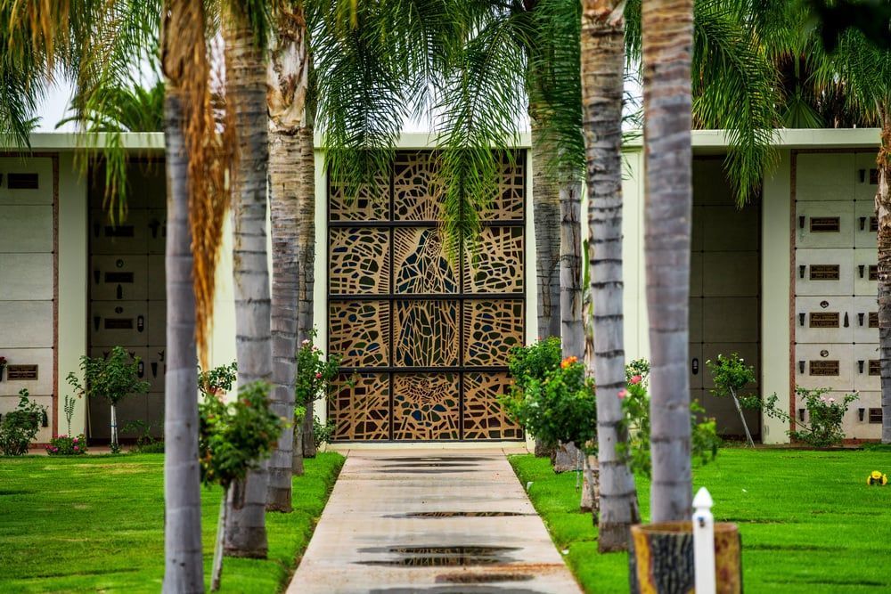 Pathway through palm trees leading to a decorative gate and white building facade