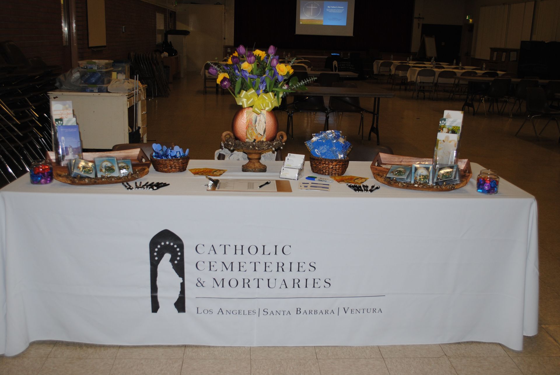 Catholic Cemeteries & Mortuaries logo with white statue silhouette on black arch