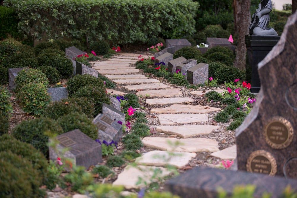 Stone garden path winding through greenery with pink flowers and memorial plaques