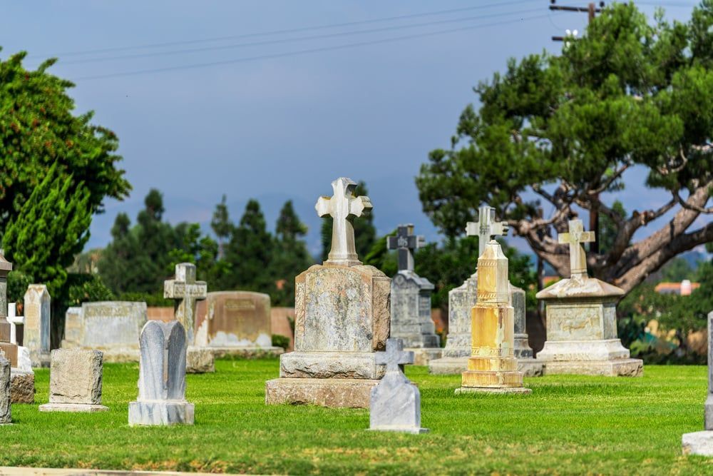 Cemetery with old stone tombstones and crosses on a green lawn under a blue sky