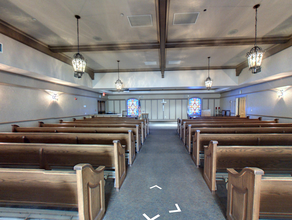 Empty church interior with wooden pews, central aisle, and hanging pendant lights